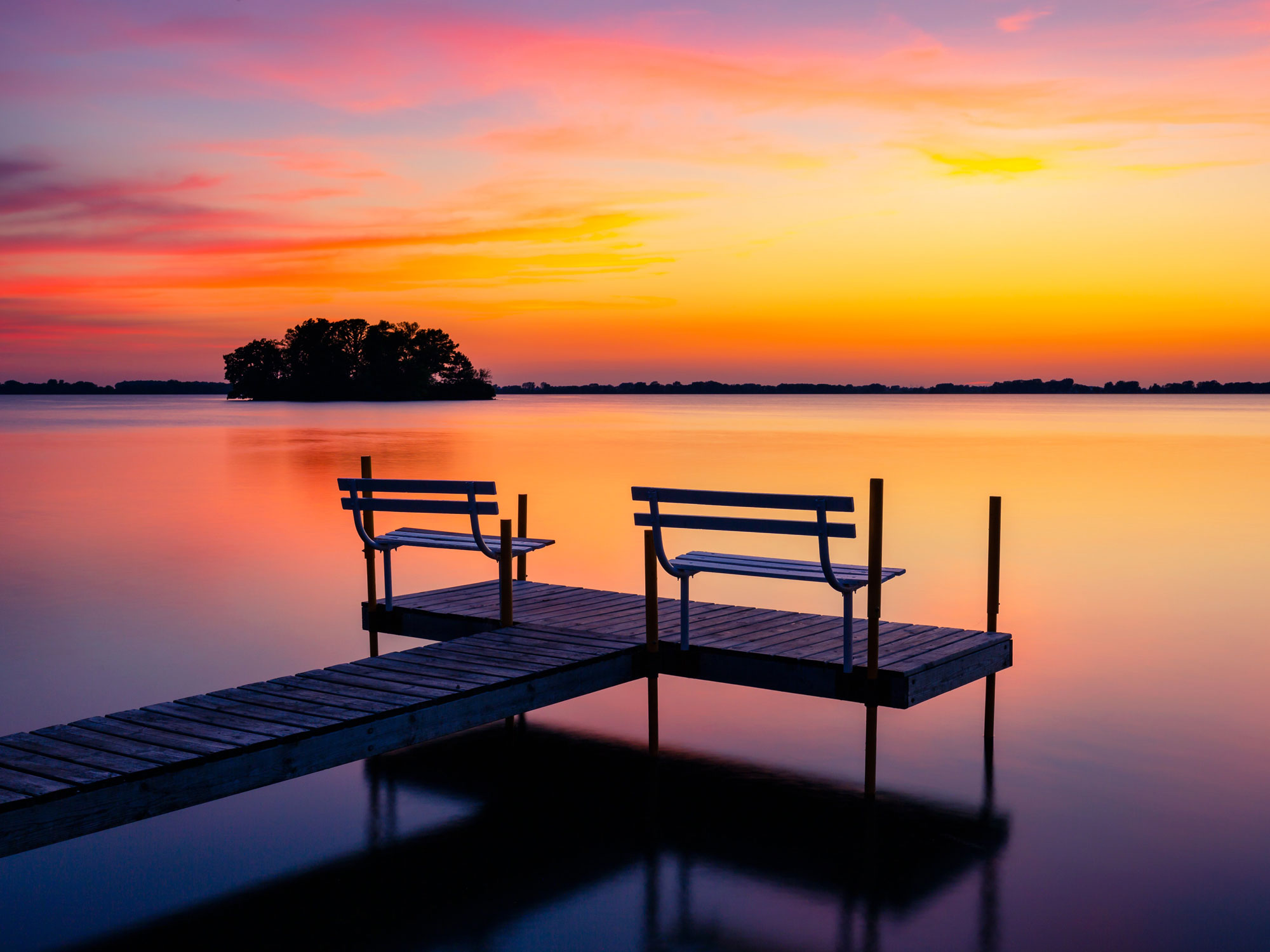 Benches on lake dock at sunset in snowy Wisconsin