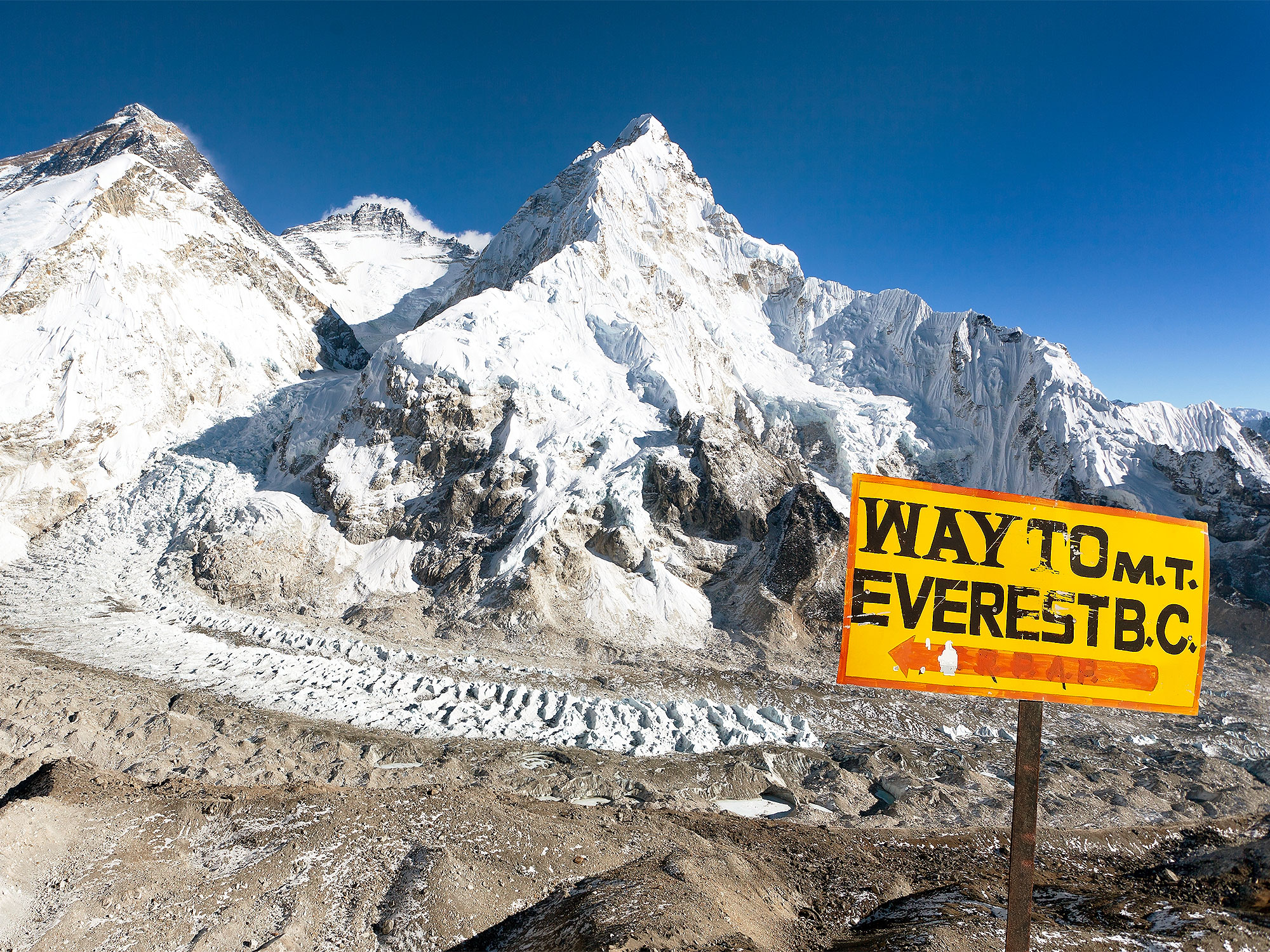 Yellow sign indicating way to Mount Everest with snowy peak in background