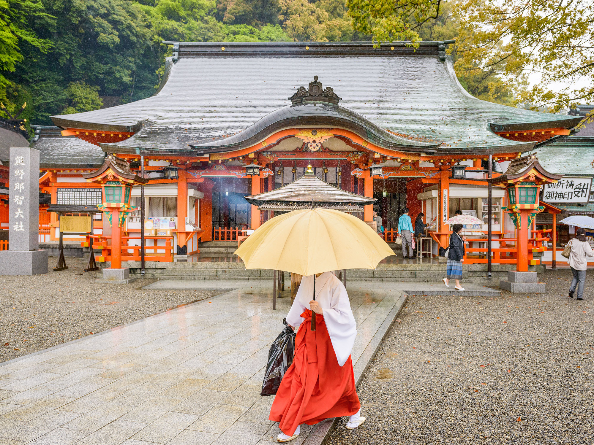 Person walking under umbrella in front of Kumano Kodo in Japan