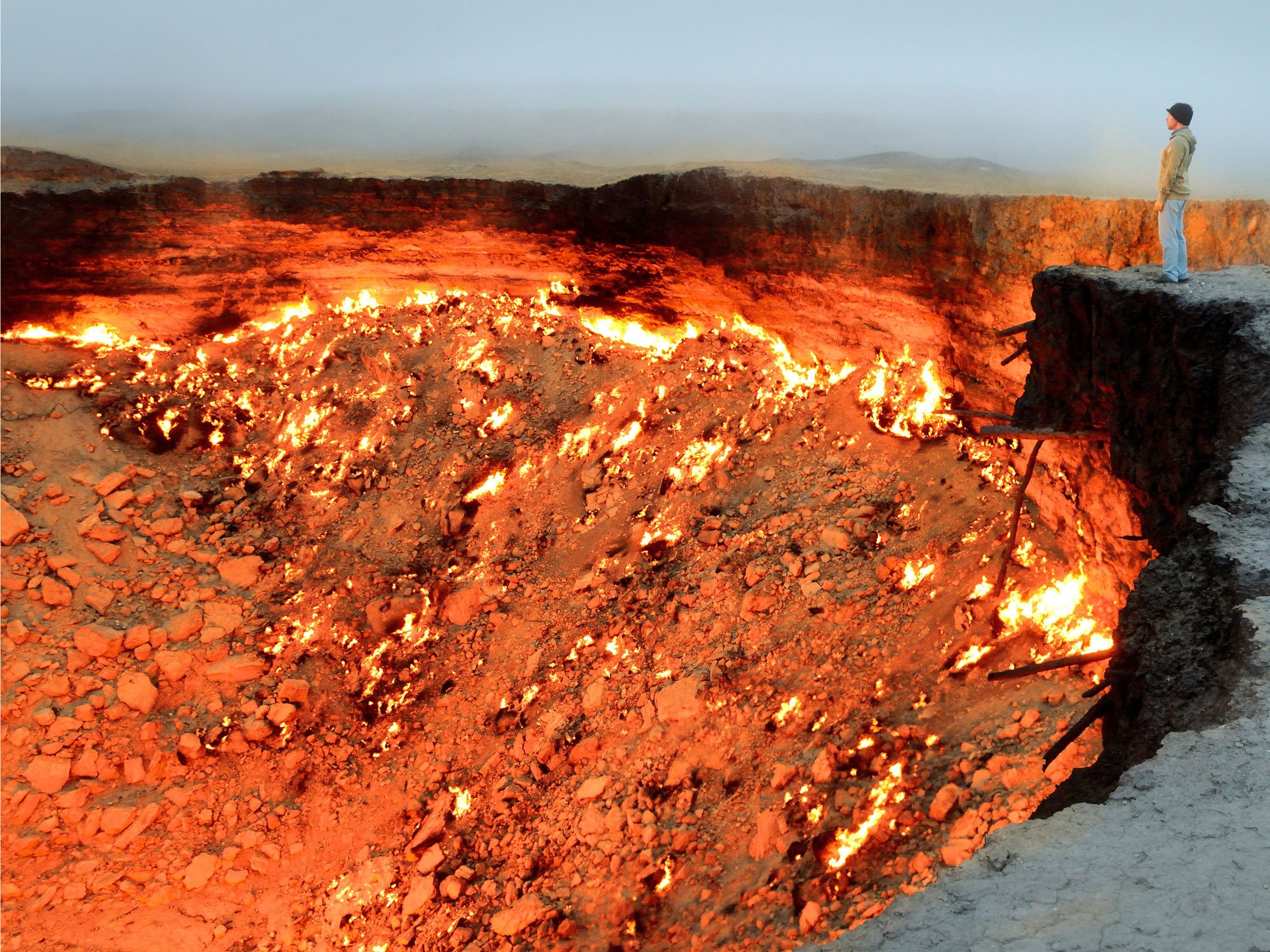 Person standing over the burning Darvaza Gas Crater in Turkmenistan's Karakum Desert