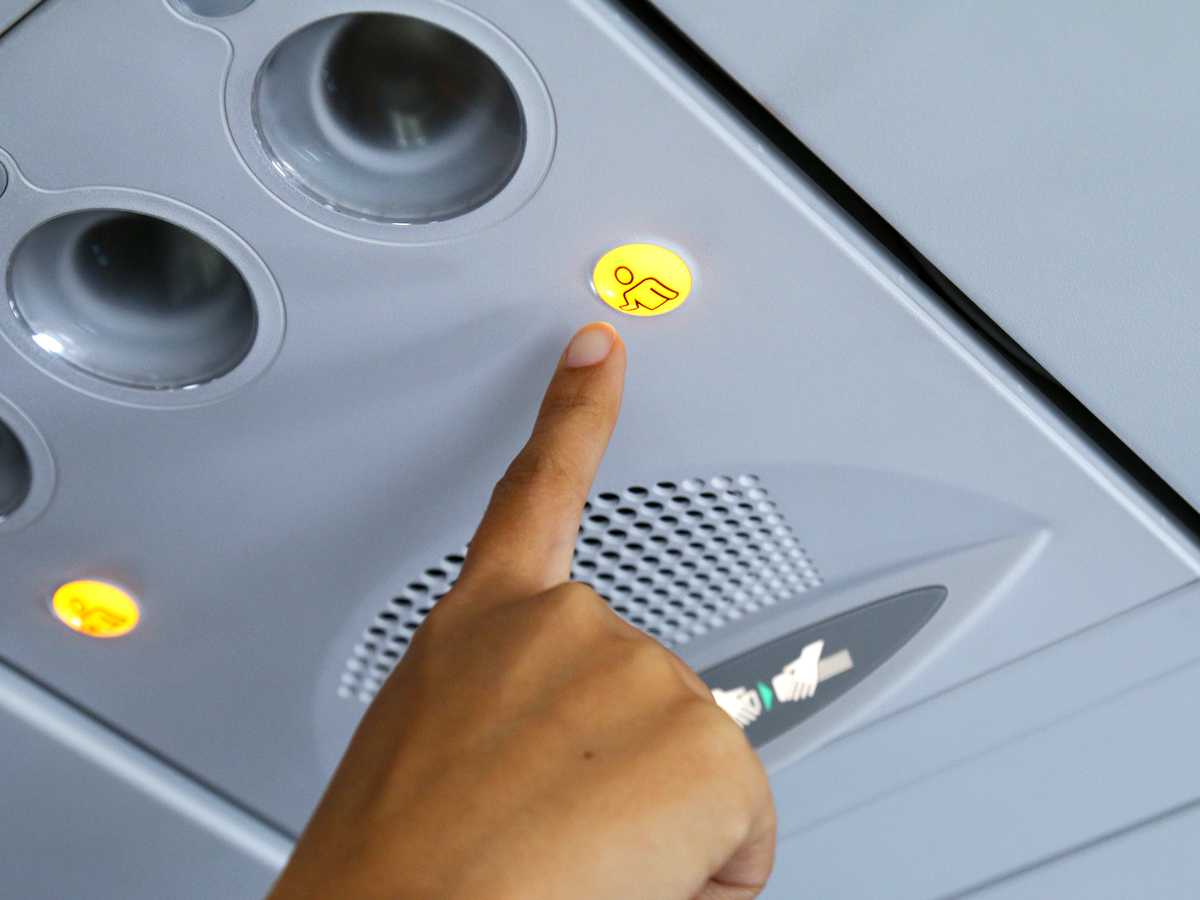 Close-up view of passenger pressing flight attendant call button on aircraft