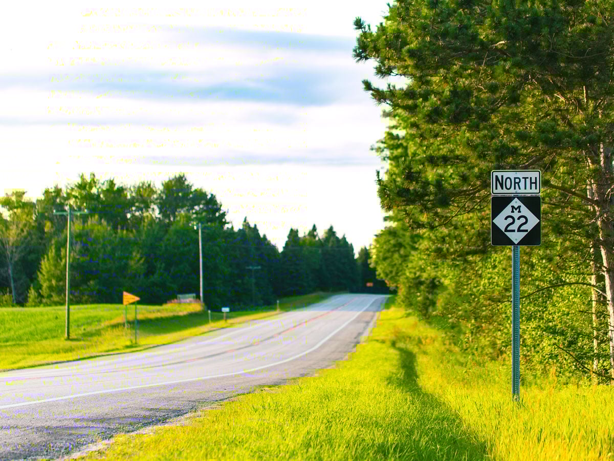 Empty two-lane stretch with sign for M-22 North in Michigan