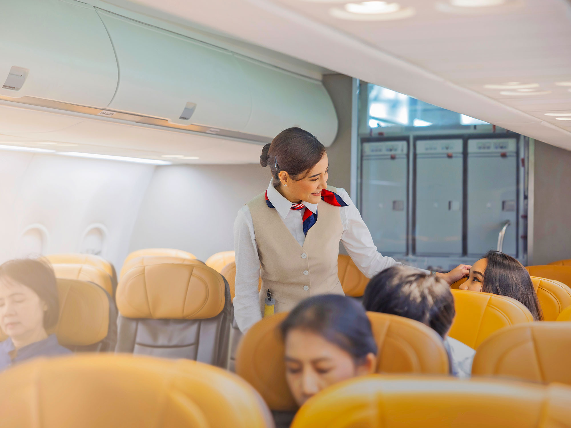 Flight attendant in aisle interacting with passenger on airplane