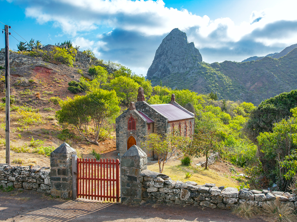 Small stone church on St. Helena Island surrounded by rocky mountain landscape