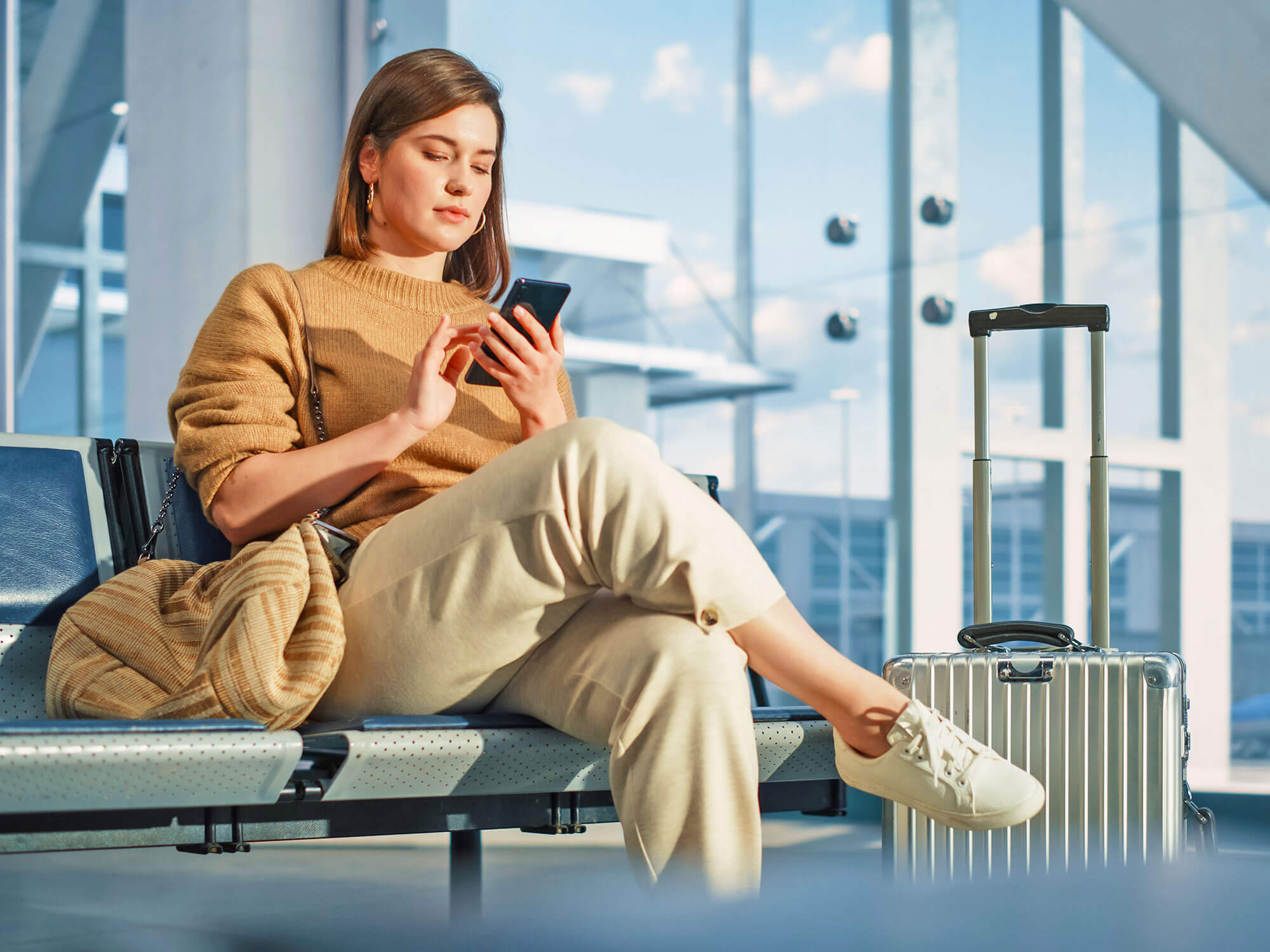Passenger sitting in airport terminal using her cell phone
