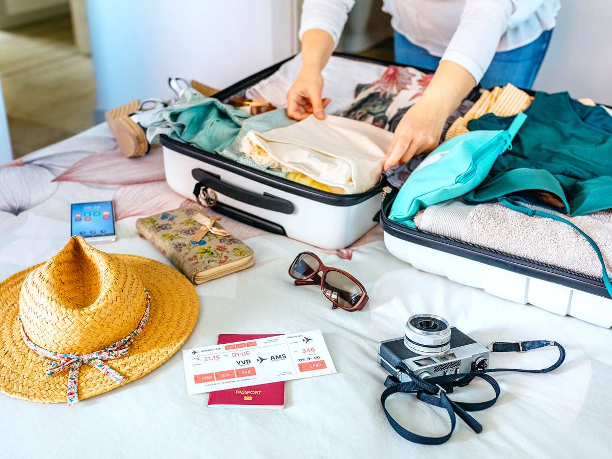 Person laying items out on bed to pack in suitcase