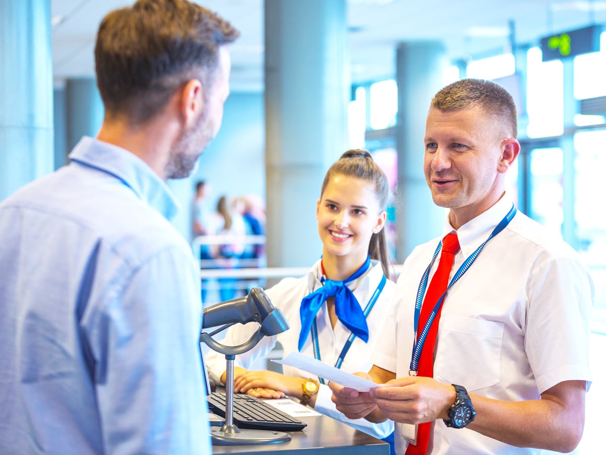 Gate agent handing passenger ticket at airport