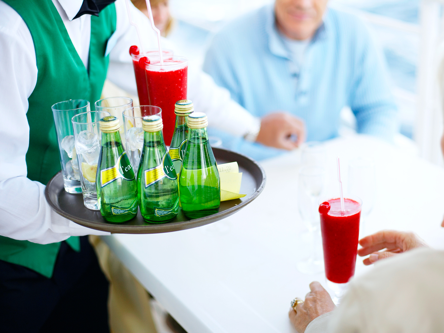 Cruise ship waiter with tray of drinks at table