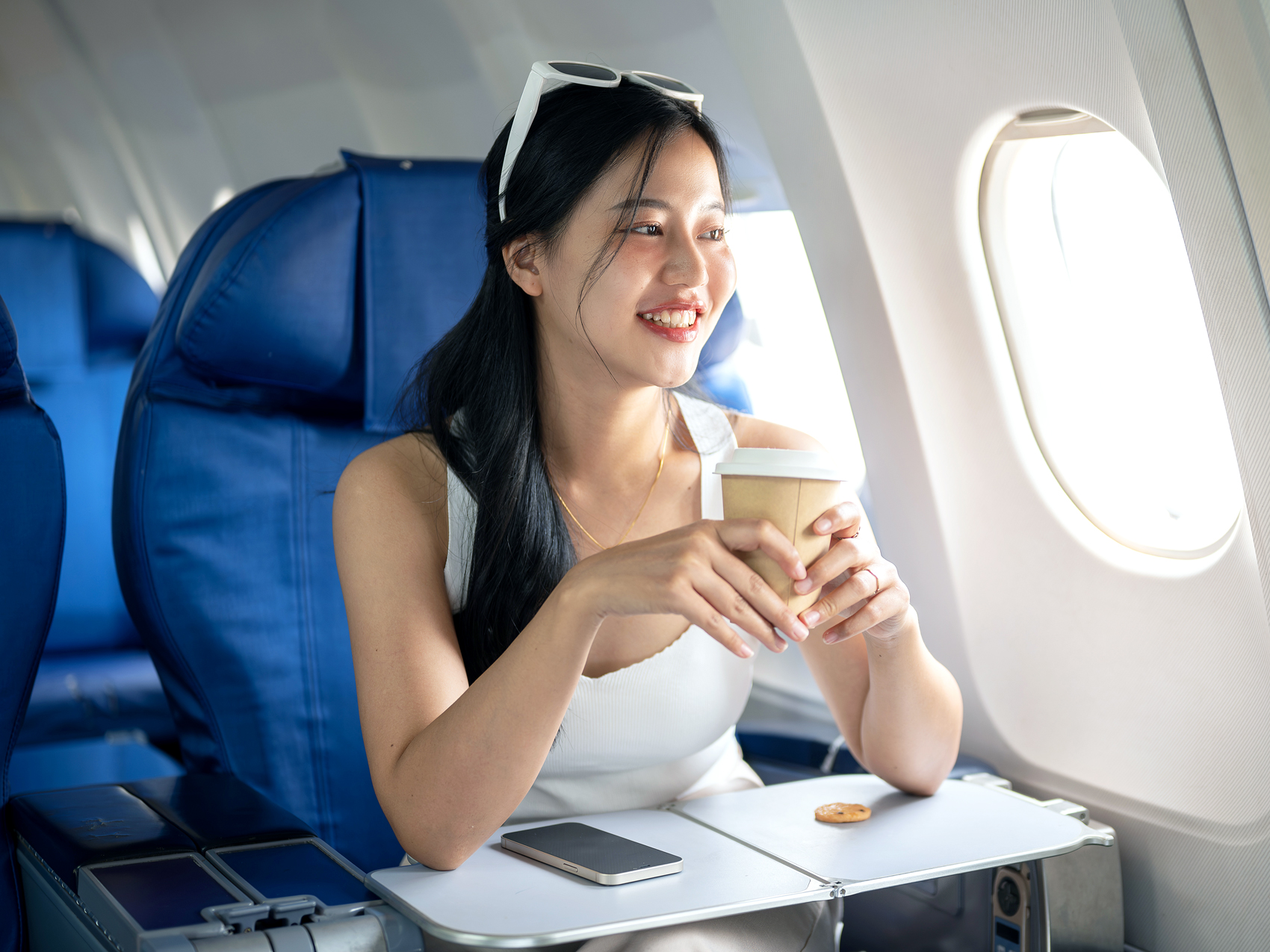 Passenger wearing tank top and holding coffee cup on airplane