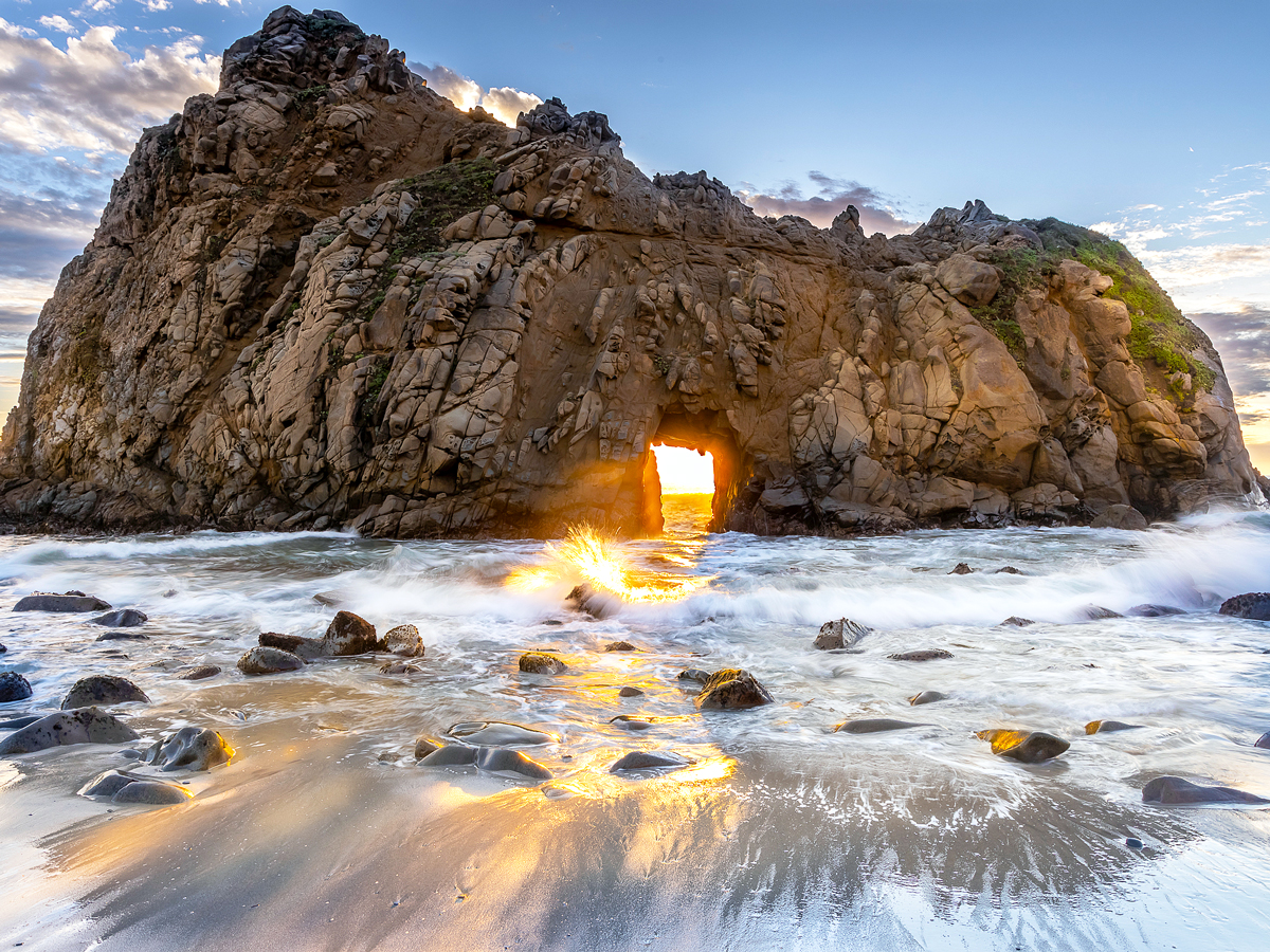 Sunset shining through Keyhole Arch off Pfeiffer Beach, California