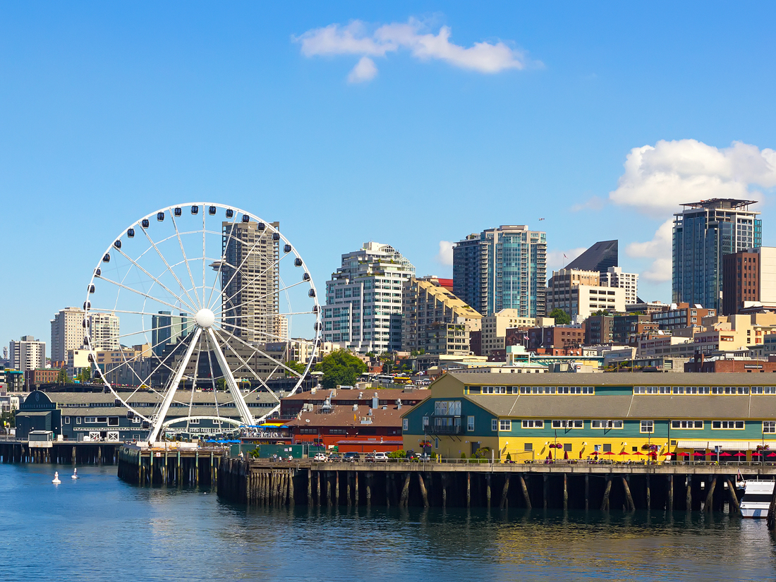 Ferris wheel along water with Seattle skyline in background