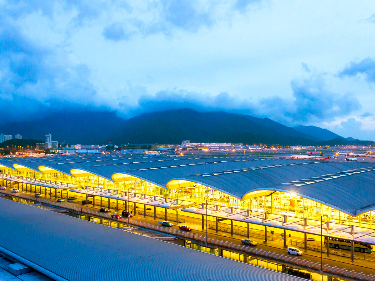 Terminal at Hong Kong International Airport lit at night with mountains in background