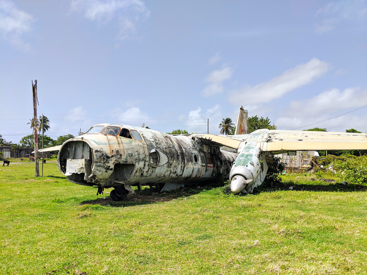 Abandoned aircraft on grassy field at Pearls Airport, Grenada 