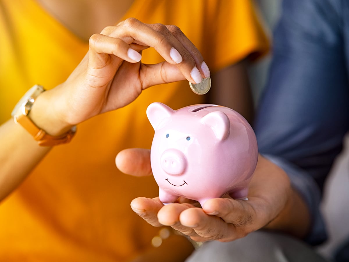 Person placing coin in miniature piggy bank