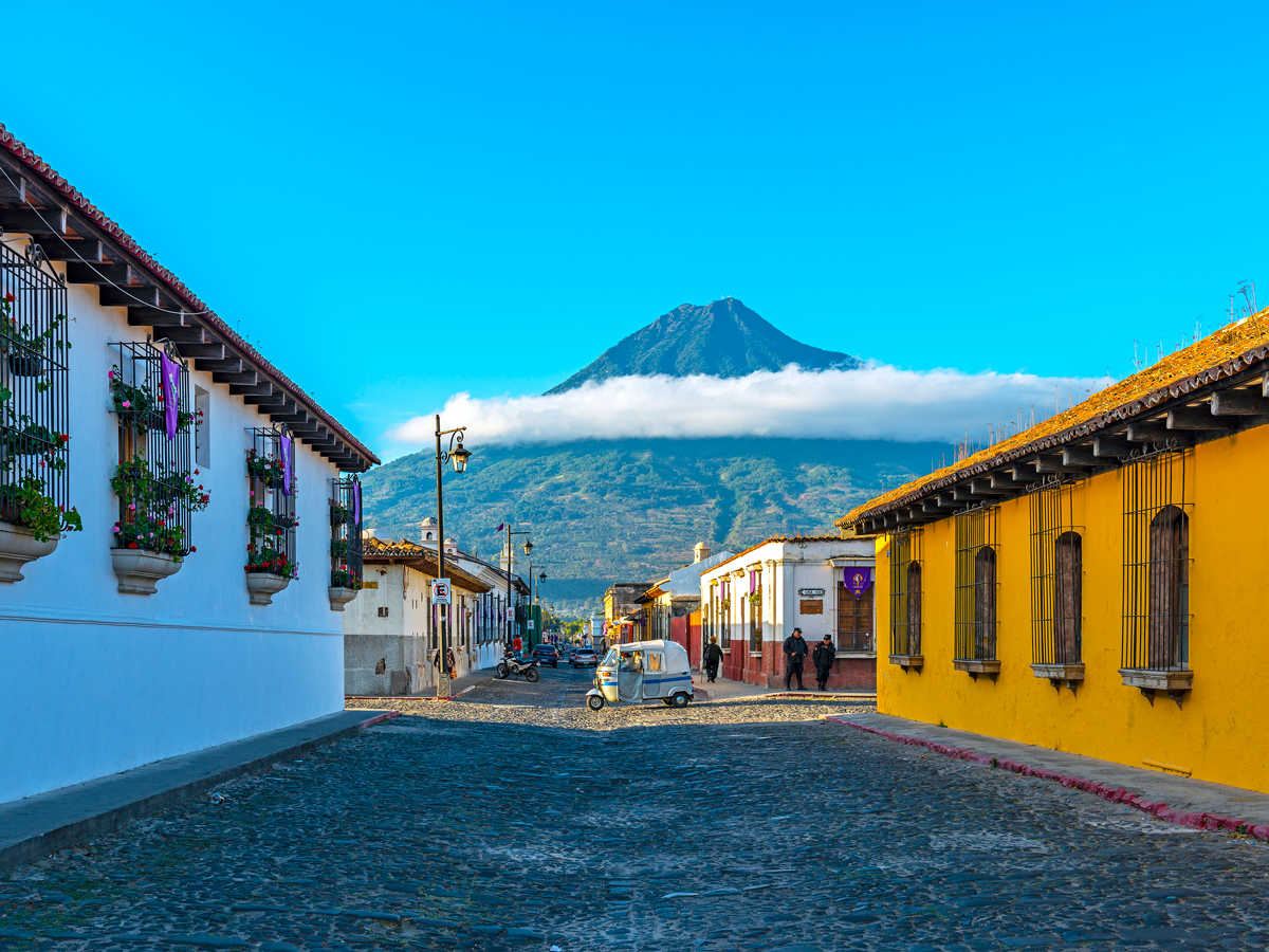 Car driving on street in Guatemala with view of volcano