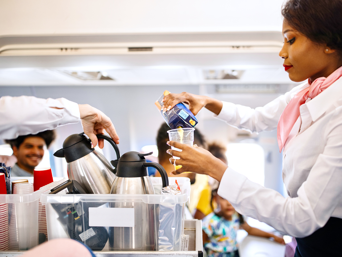 Flight attendants pouring beverages in aircraft aisle