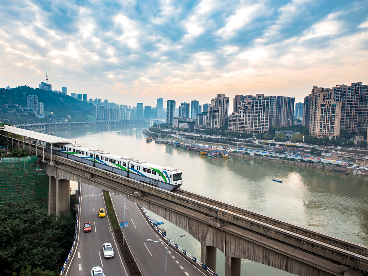 Elevated train with river, skyline, and clouds above Chongqing, China