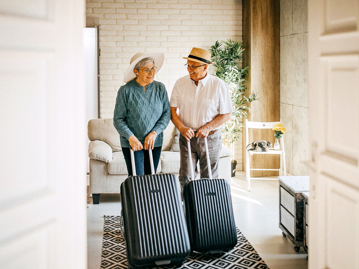 Older couple rolling suitcases into hotel room