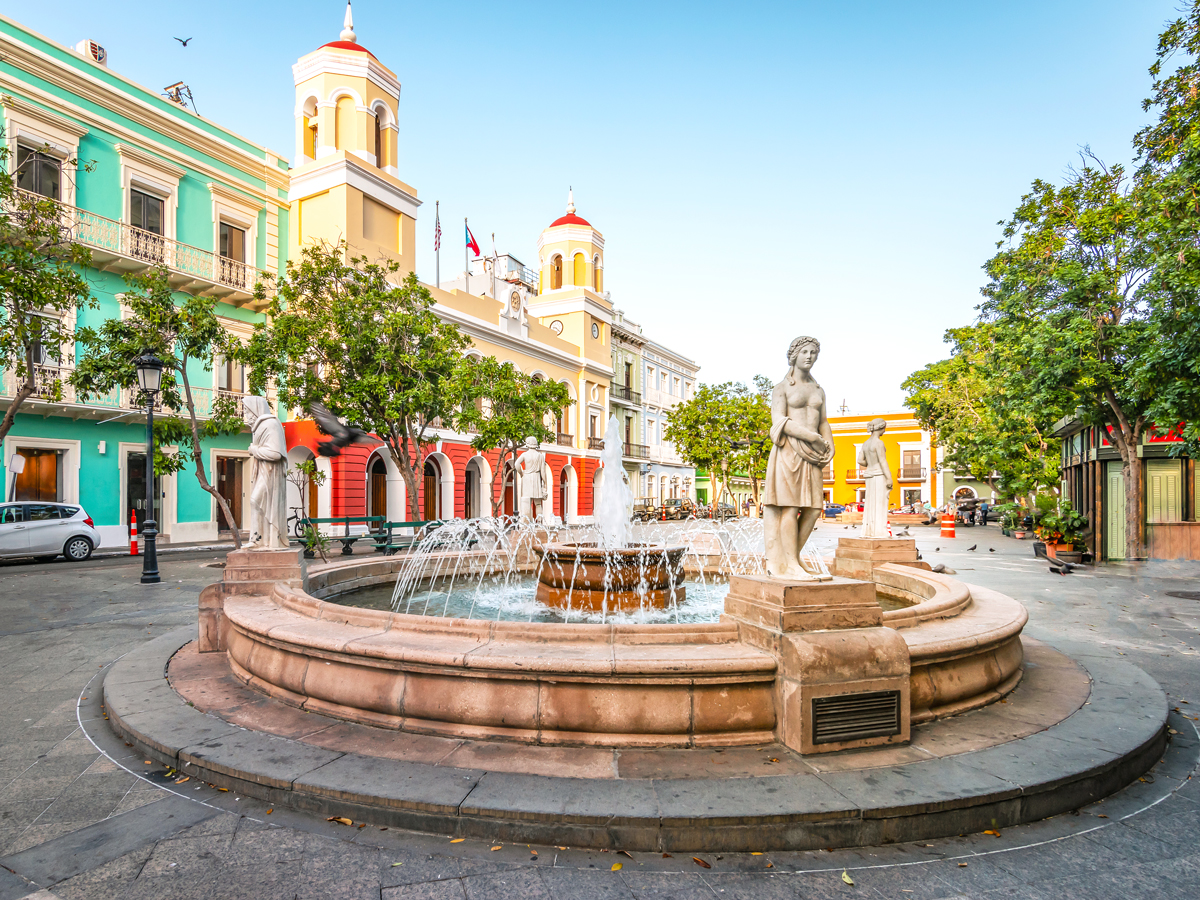 Statues surrounding fountain beside colorful architecture in Old San Juan, Puerto Rico