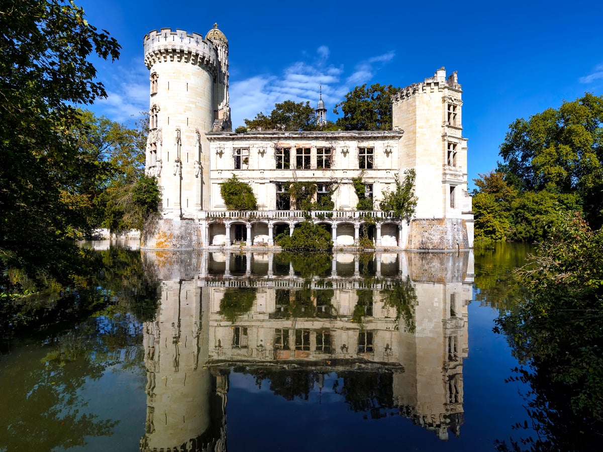 Abandoned Château de la Mothe Chandeniers in France with reflection on lake