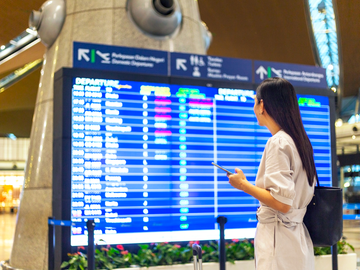 Airline passenger looking at departures and arrival board in airport terminal