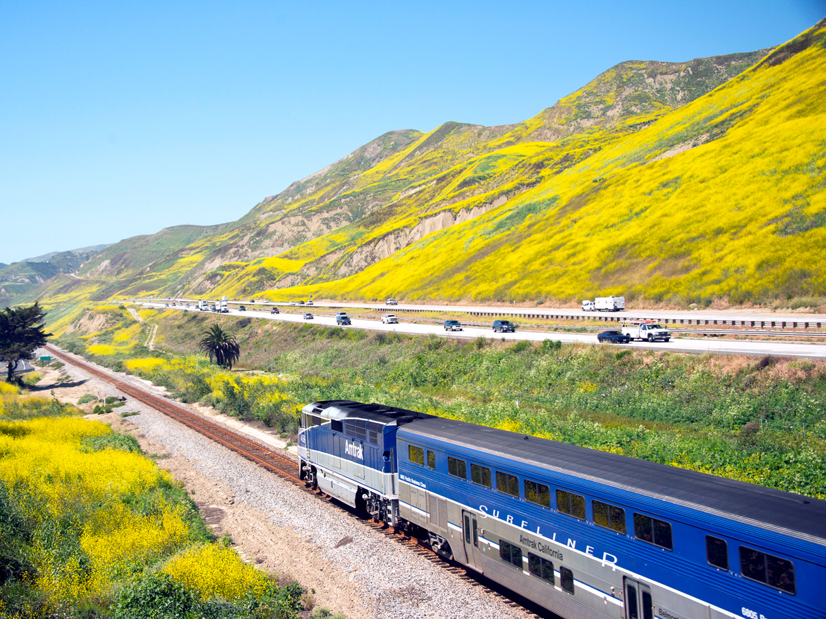 Amtrak Pacific Surfliner train alongside motorway and mountains