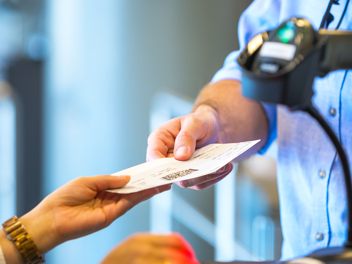 Passenger handing boarding pass to airport employee