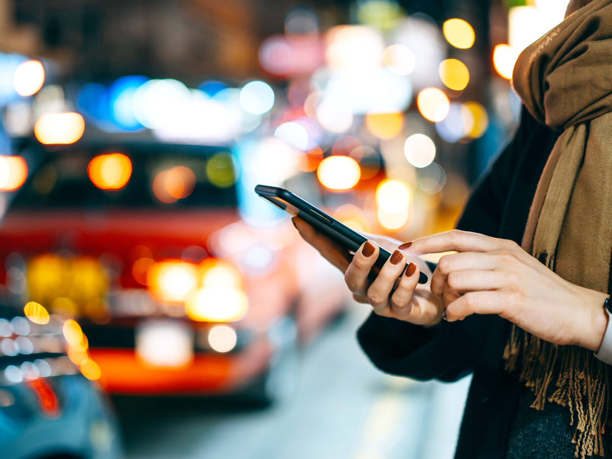 Person standing on street holding cellphone