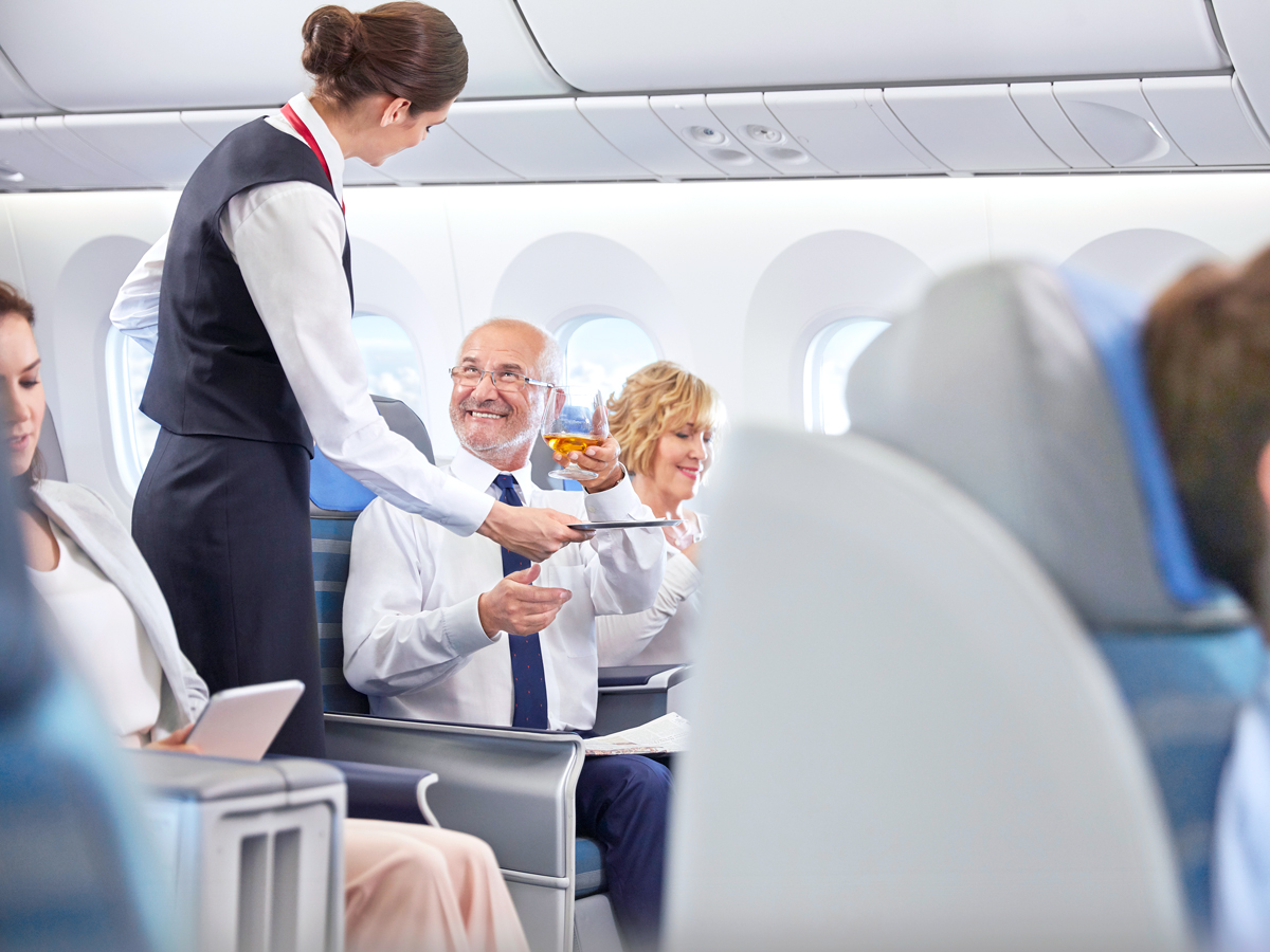 Flight attendant serving beverage to passenger