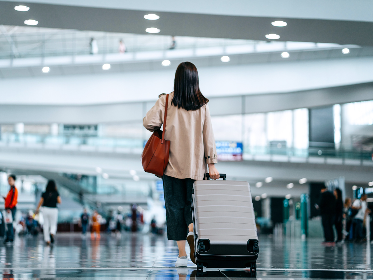 Passenger rolling suitcase through airport