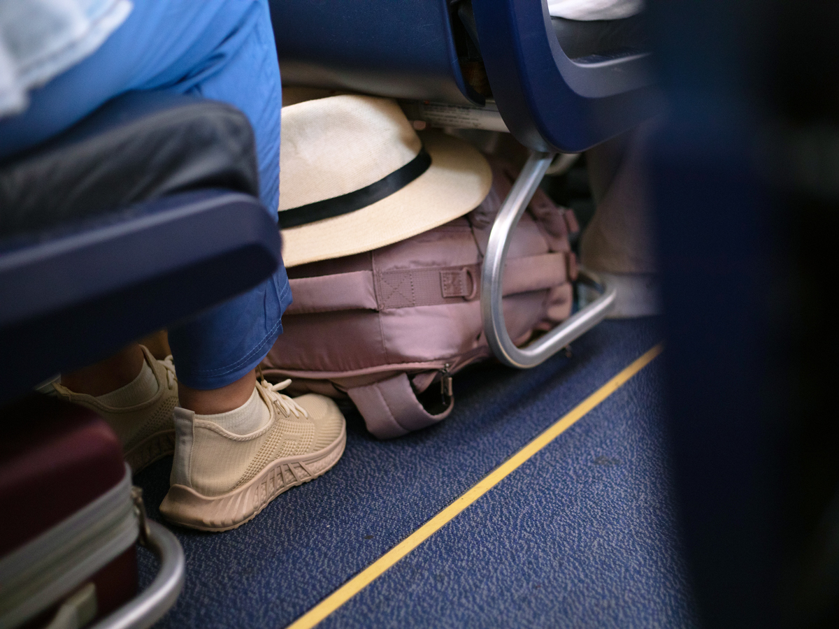 Hat and backpack tucked under aircraft seat