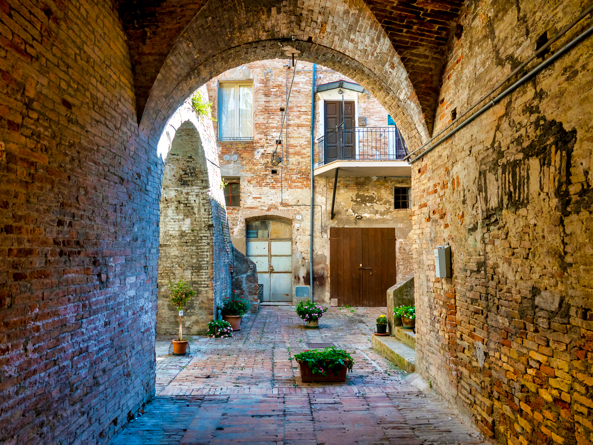 Stone archway and courtyard in village of Penne, Italy