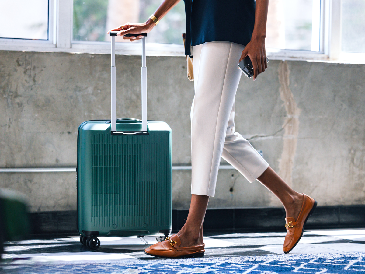 Close-up of traveler's shoes and suitcase in airport