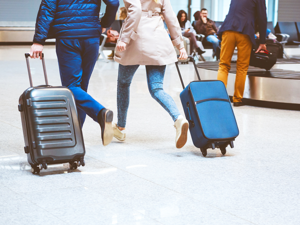 Travelers rolling suitcases through airport