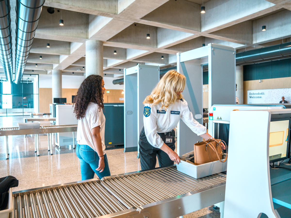 Officer placing bin through X-ray scanner at airport security checkpoint