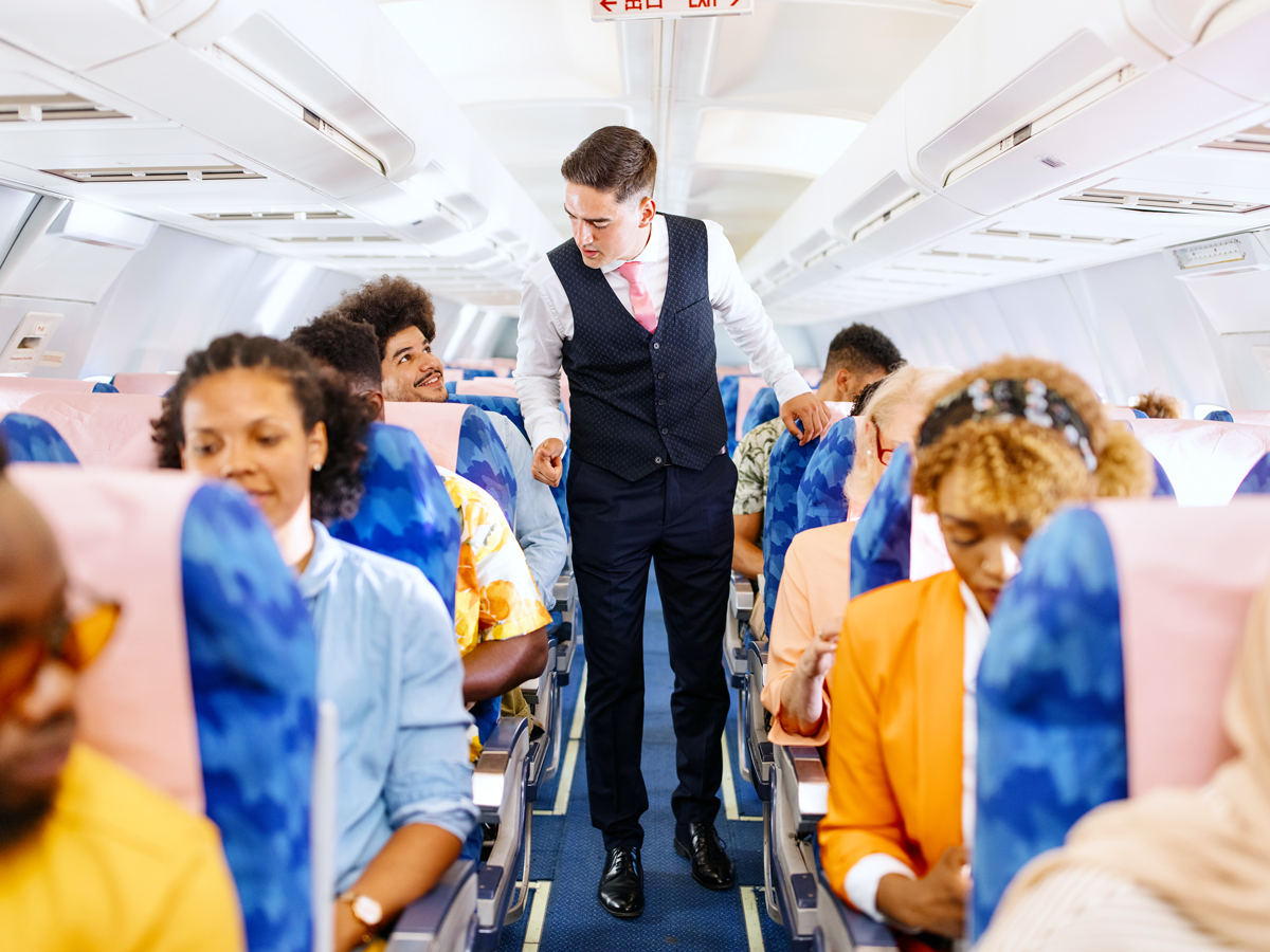 Flight attendant walking down aisle checking on passengers
