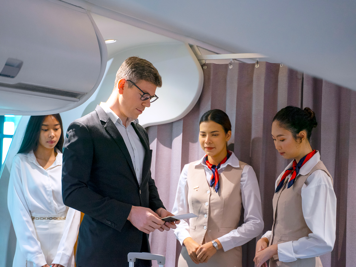 Flight attendants welcoming passengers as they board plane