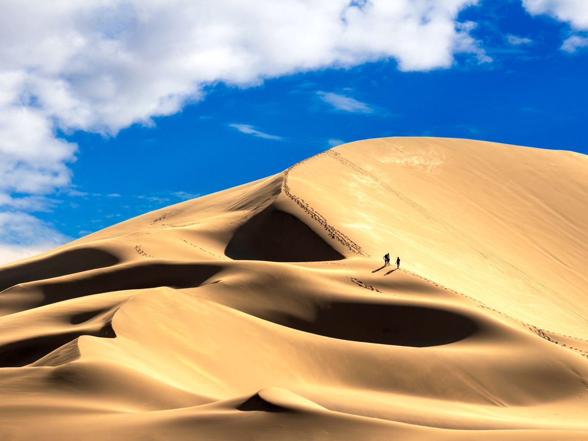 Two people climbing along ridge of Dune 7 in Namibia