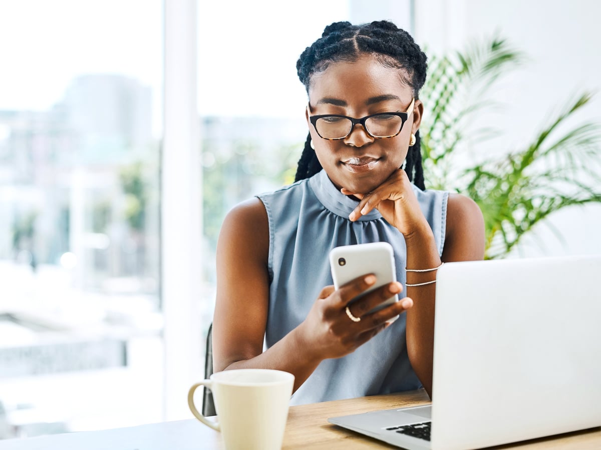 Woman sitting at desk with phone and laptop