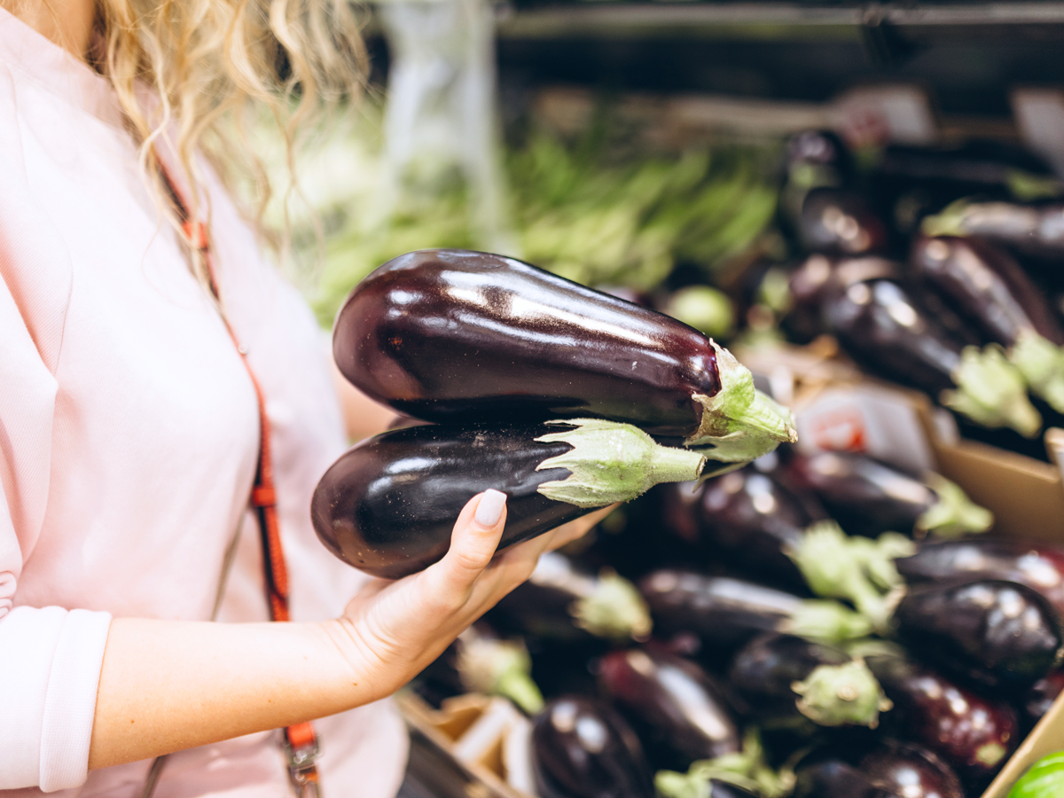Shopper selecting eggplants at grocery store