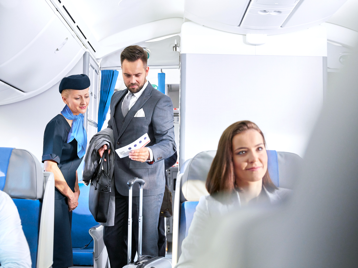 Flight attendant and passenger standing in aircraft aisle