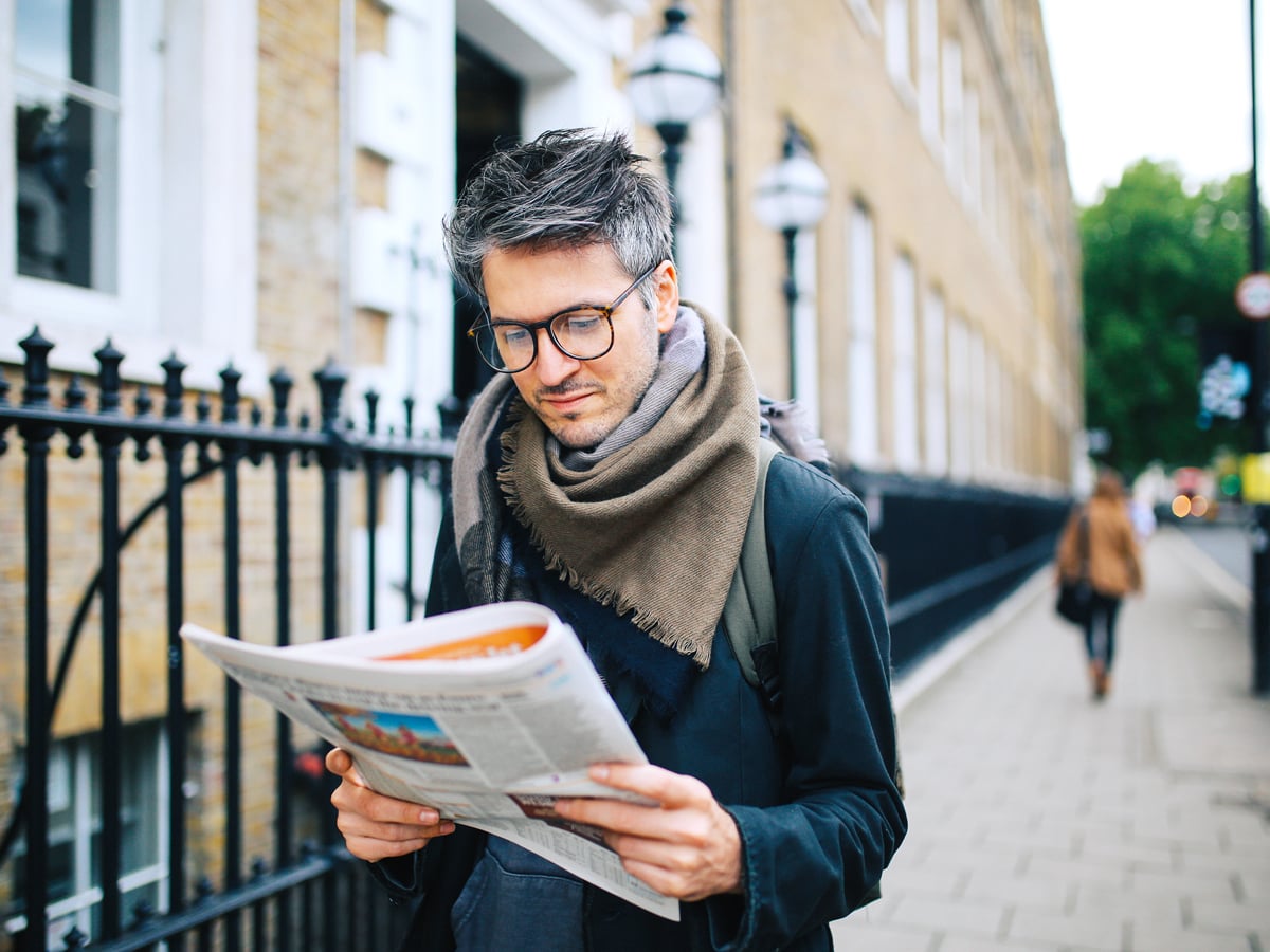 Man reading newspaper on street