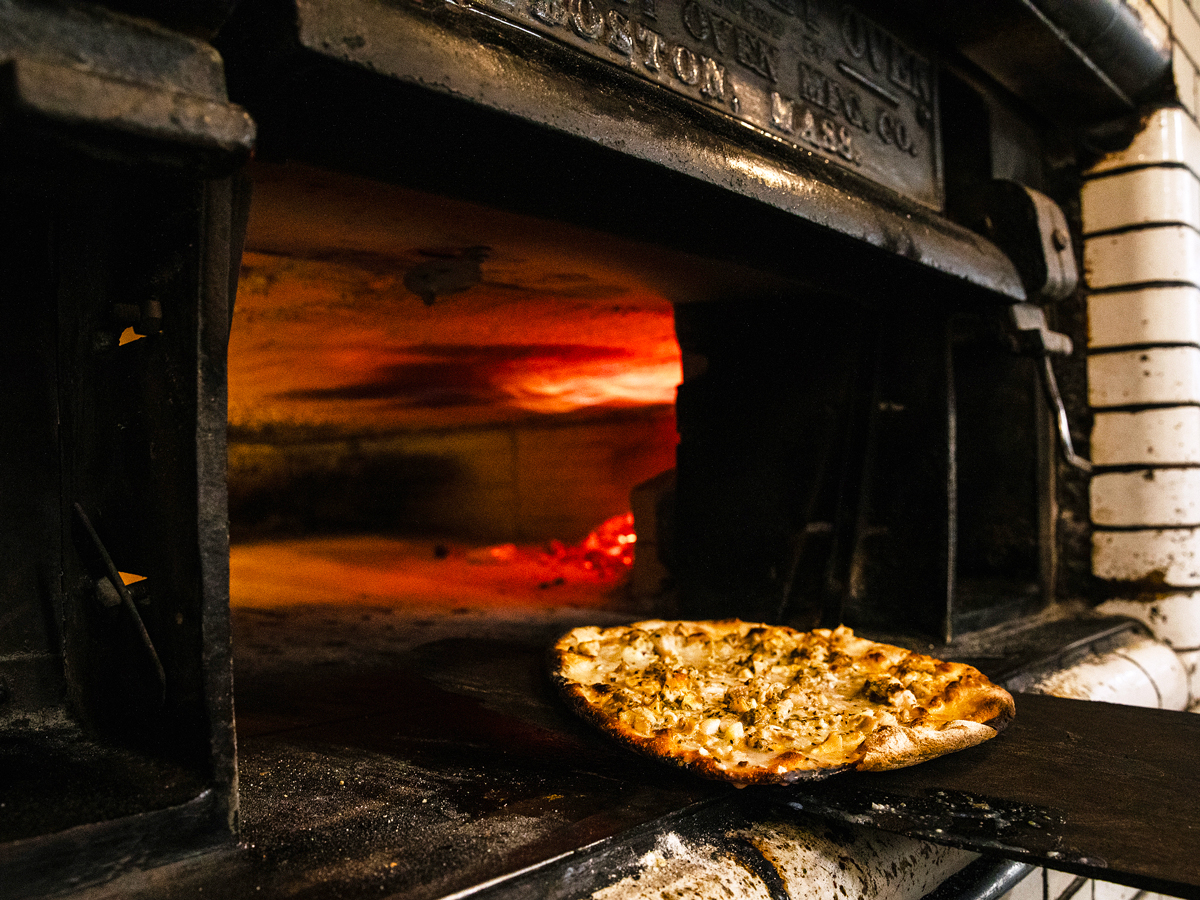 Chef placing New Haven-style pizza in oven