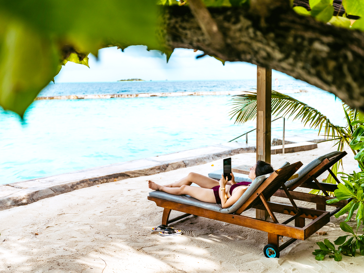 Person lounging on beach chair with tablet