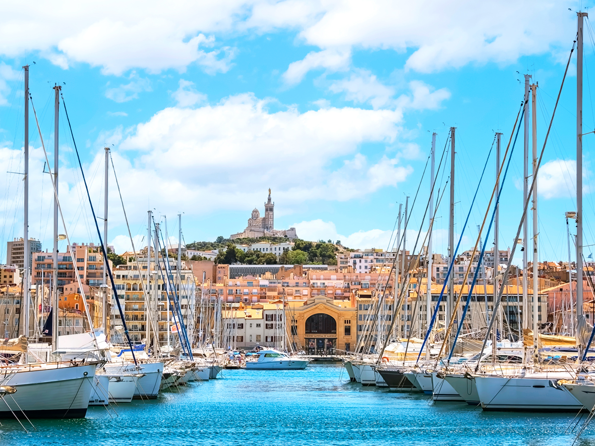 Sailboats docked in harbor with view of Marseille skyline
