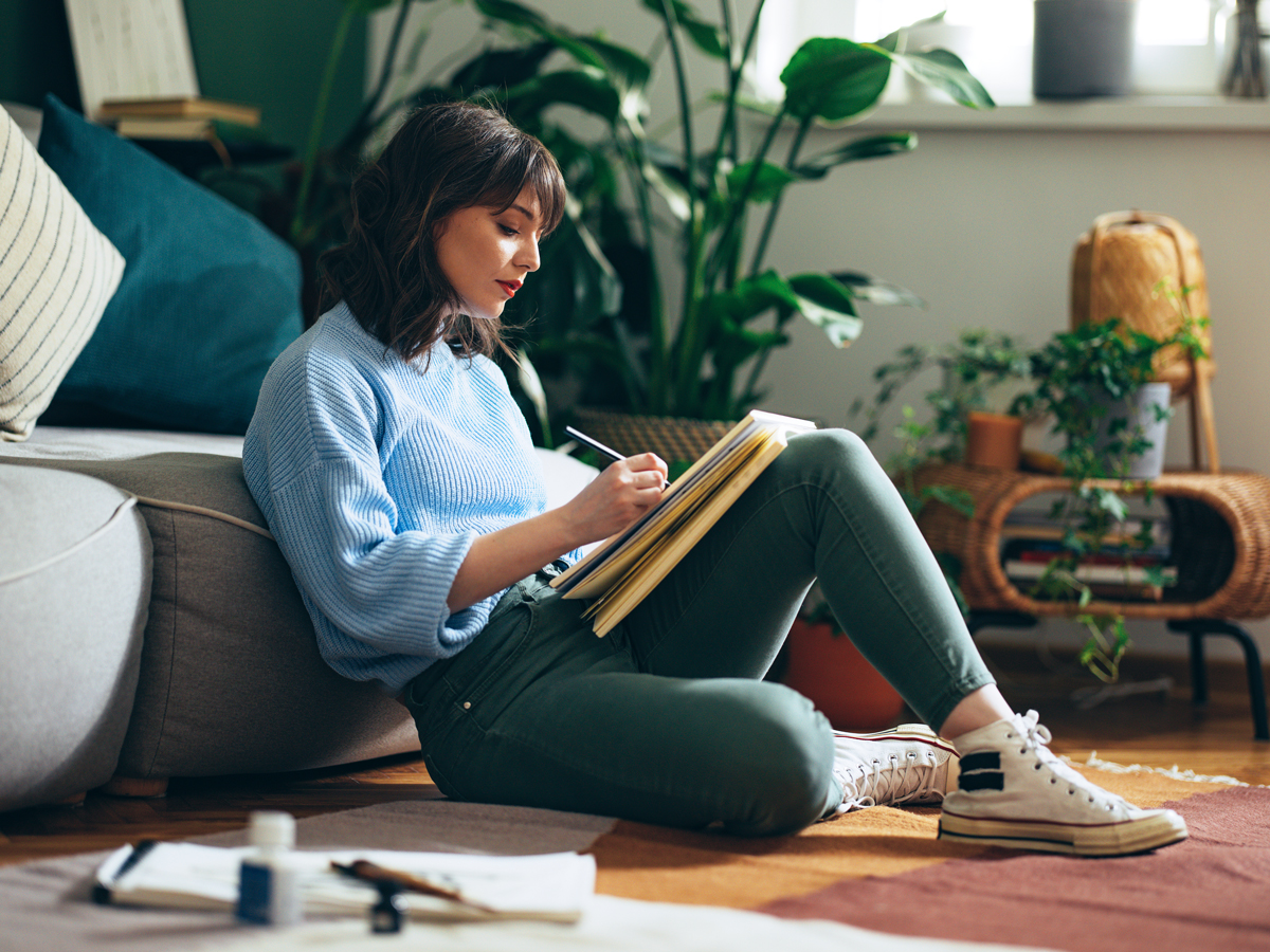 Person sitting on floor writing in notebook