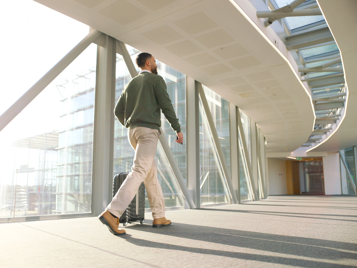 Traveler rolling luggage through airport terminal