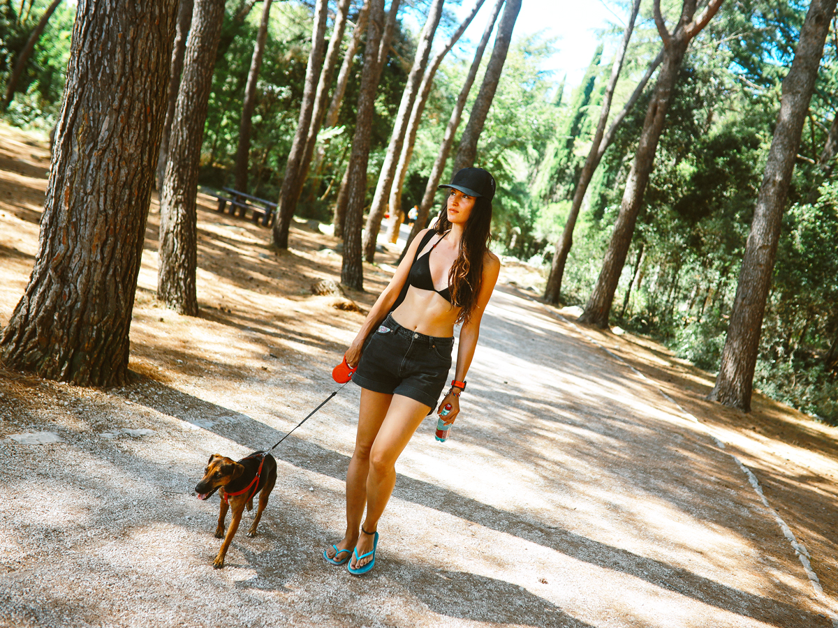 Woman wearing swimsuit and walking dog