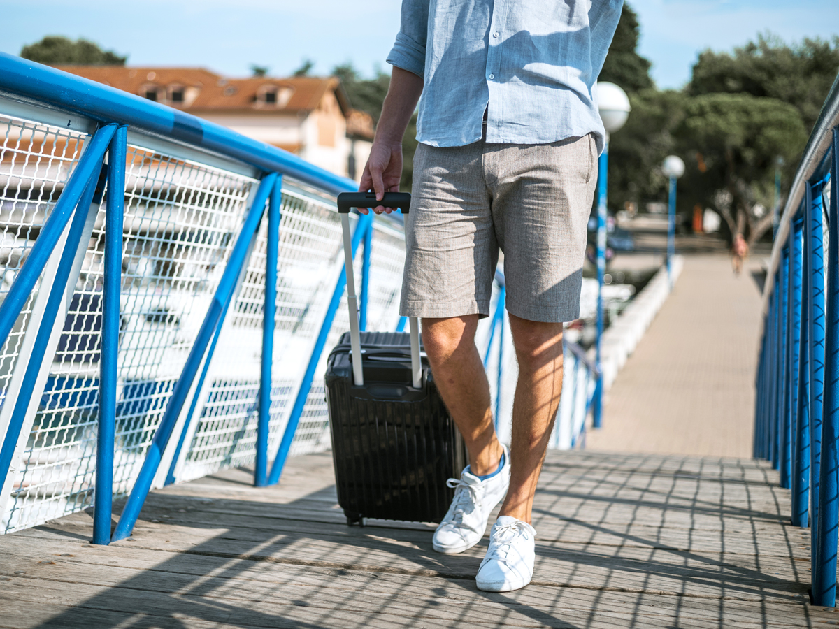 Passenger wheeling suitcase on ramp to board cruise ship
