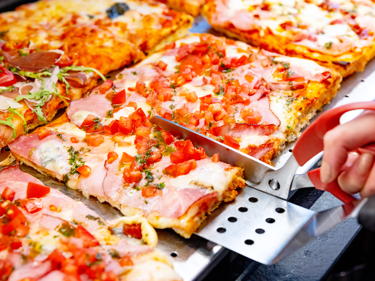Person cutting slices of pizza made in the style of the Quad Cities of Iowa and Illinois